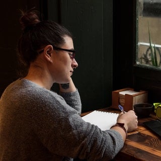 A young student works on a table near a pub window.  Close up view Alicante, Valencian Community, Spain 