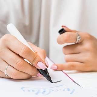 Handlettering: Eine Frau schreibt in auf ein Blatt Papier