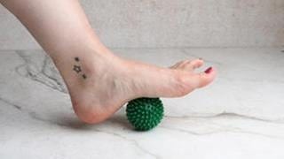 Der linke Fuß rollt mit der Fußsohle über einen Igelball.