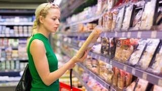 Frau liest Zutatenliste beim Lebensmitteleinkauf