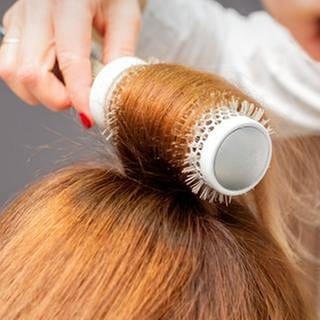 Haare werden beim Frisör mit einer Rundbürste gestylt