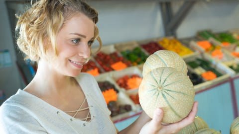 Frau im Supermarkt schaut sich Melonen an