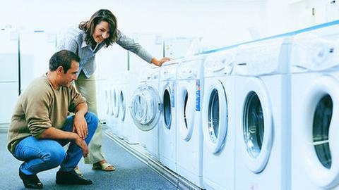 Ein Paar berät sich bei Waschmaschinenkauf in einem Fachgeschäft.