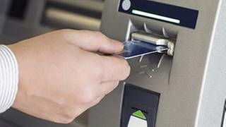 Ein Mann steckt eine Karte in einen Geldautomat