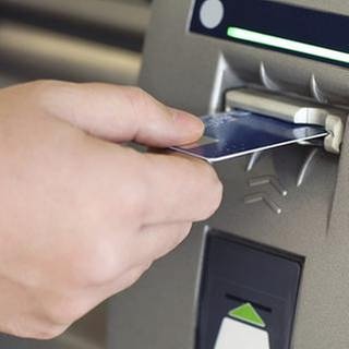 Ein Mann steckt eine Karte in einen Geldautomat