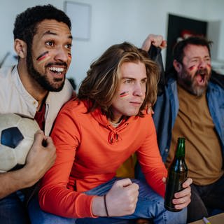 Drei Männer schauen sich ein Fußballspiel an