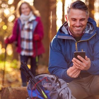 Paar bei einer Wanderung im Wald mit Smartphone