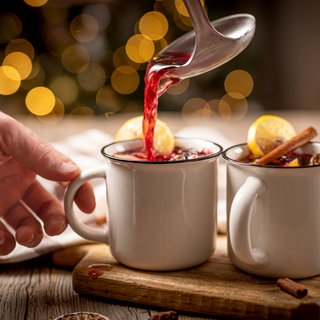 Glühwein wird mit einer Kelle in Tassen geschöpft