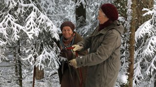 Johanna und Lioba im verschneiten Wald, Johanna hält eine Säge