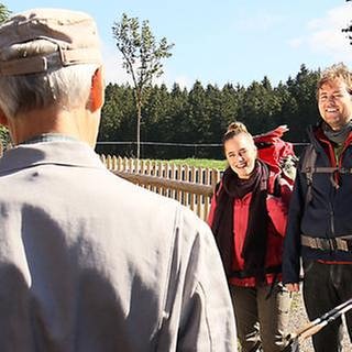 Karl, den man von hinten sieht, trifft vor dem Hof auf zwei Wanderer