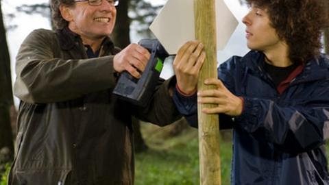 Bernhard und Albert bringen ein Schild im Wald an