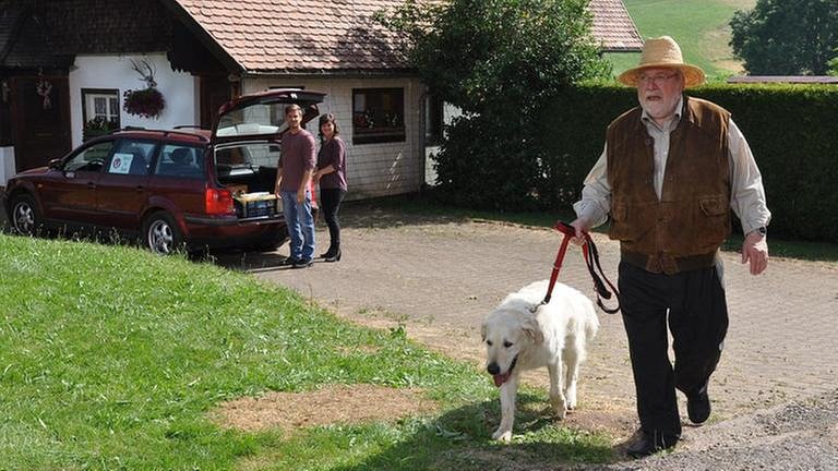 Hermann läuft mit Willy den Weg entlang, im Hintergrund sieht man Eva und Andreas