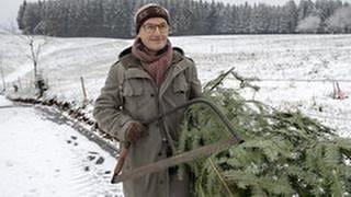 Karl hat einen Weihnachtsbaum geschlagen und trägt ihn zum Fallerhof