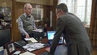 Herr Weiss und Bernhard im Bürgermeisterbüro, vor ihnen auf dem Schreibtisch ein großer Stapel Briefe