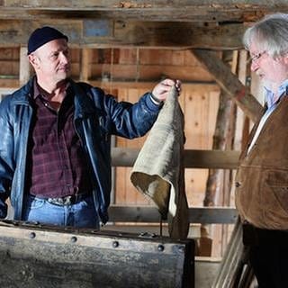 Toni hält Hermann in der Mühle einen alten Lappen hin