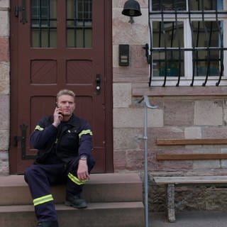 Uli Zimmermann sitzt auf dem Stufen vor dem Feuerwehrhaus