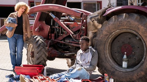 Bea und Tayo bei Karls altem Traktor, Tayo sitzt angelehnt an den Traktor