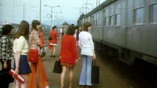 Mehrere junge Frauen am Bahnsteig, rechts ein dunkelgrauer Zugwaggon