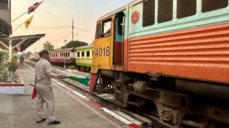 Mit grünen Fahnen geben die Fahrdienstleiter an den thailändischen Bahnhöfen die Einfahrt frei.