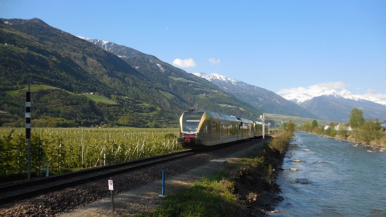 Die Vinschgaubahn auf ihrer Strecke zwischen Mals und Meran. Im Tal ist die Etsch ihr ständiger Begleiter.