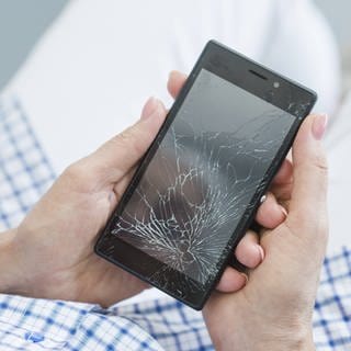 Frau hält Smartphone mit einem gebrochenen Handy-Bildschirm.