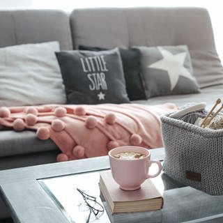 Couch mit Kissen und Häkelkorb mit Wolle auf dem Tisch