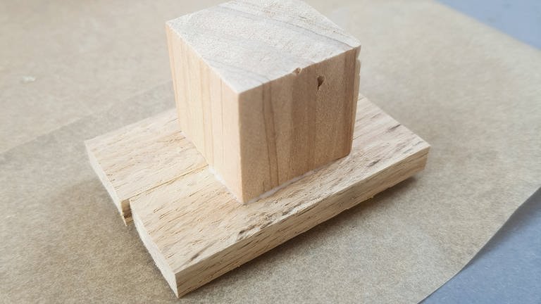 Um noch einfacher Stempeln zu können, auf die Rückseite einen kleinen Holzwürfel, Holzrest oder eine große Holzperle aufleimen.