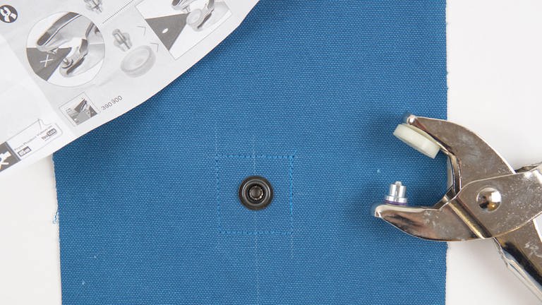 Das markierte Loch mit der Lochzange oder dem Lochwerkzeug lochen und den unteren Teil des Druckknopfes nach Herstellerangabe am Korpus anbringen. 