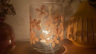 Die laminierte Folie dient nun als Manschette für eine Vase oder ein Glas. Die Breite oder Höhe der Folie kann mit der Schere angepasst werden. Die Manschette am Schluss mit etwas transparentem Klebefilm verschließen. 