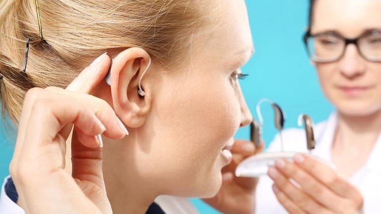 Frau kriegt ein passendes Hörgerät von einer Ärztin