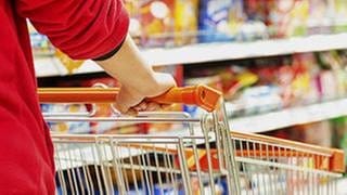 Person schiebt ihren Einkaufswagen durch die Gänge eines Supermarktes.