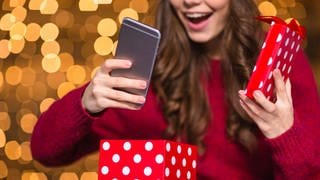 Frau packt Weihnachtsgeschenk Smartphone aus