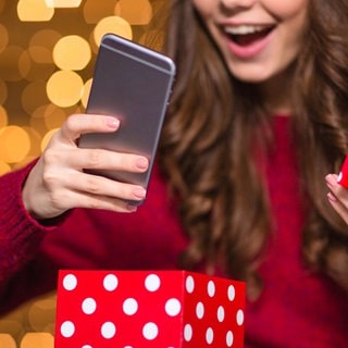 Frau packt Weihnachtsgeschenk Smartphone aus