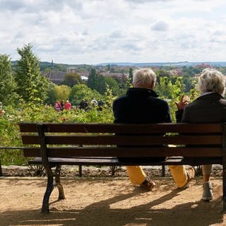 Rente genießen: Ein älteres Paar sitzt auf einer Parkbank