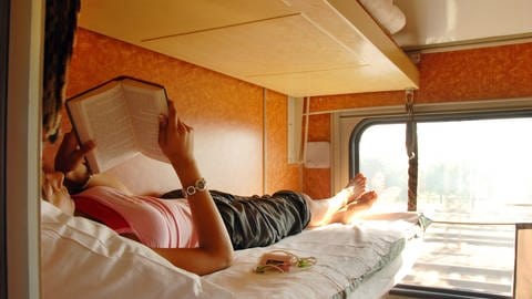 Frau im Zug liest auf der Urlaubsreise