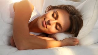 Frau mit gesundem Schlaf in frischer Bettdecke und Kissen