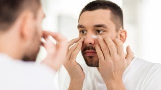 Mann cremt Gesicht ein - Hautpflege im Winter