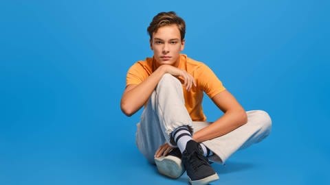 Junger Mann in orangefarbenem T-Shirt und weißer Jogginghose  Kuschellook fürs Sofa  Mode