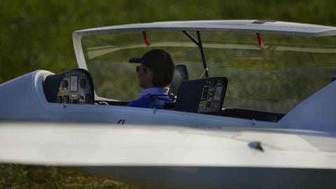 Mann sitzt im Cockpit eines Modellflugzeugs