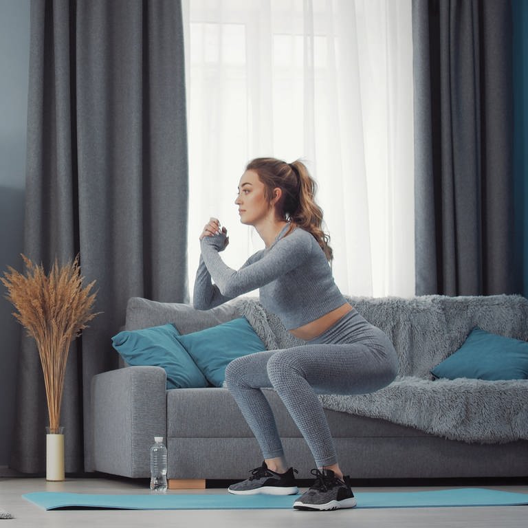 Frau macht Kniebeugen - 5-Minuten-Fitness: So schonen Sie Ihren unteren Rücken