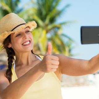 Eine Frau macht ein Selfie an einem Strand - Tipps und Tricks zur Gestaltung von guten Fotos