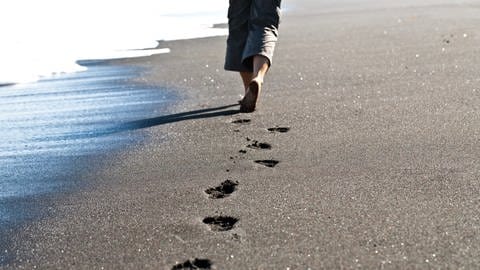 Mann läuft barfuss am Strand - vorbeugen gegen hallux valgus 