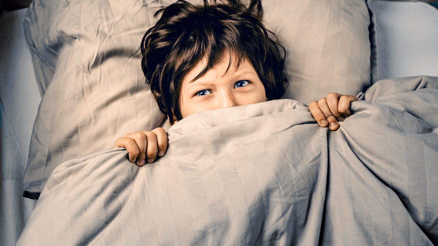 Junge liegt ängstlich im Bett