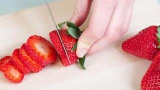 Eine Frau schneidet Erdbeeren auf.