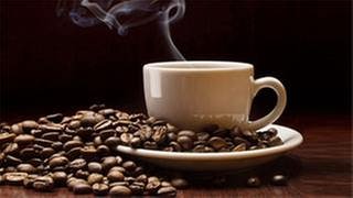 geröstete Kaffeebohnen und eine Tasse frischgebrühten Kaffee