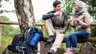 Frau und Mann machen Pause beim Wandern und Essen etwas