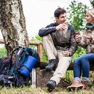 Frau und Mann machen Pause beim Wandern und Essen etwas