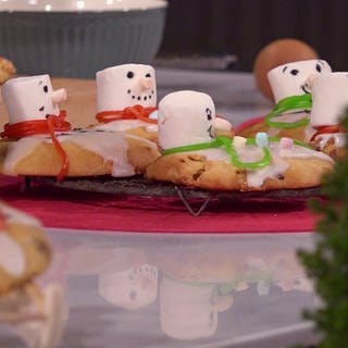 Schneemann-Cookies angerichtet auf Servierplatte in weihnachtlichem Arrangement