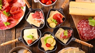Raclette-Pfännchen mit Kartoffeln, Käse, Gemüse und Schinken