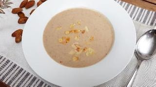 weißer Teller mit brauner Suppe mit Mandeln bestreut